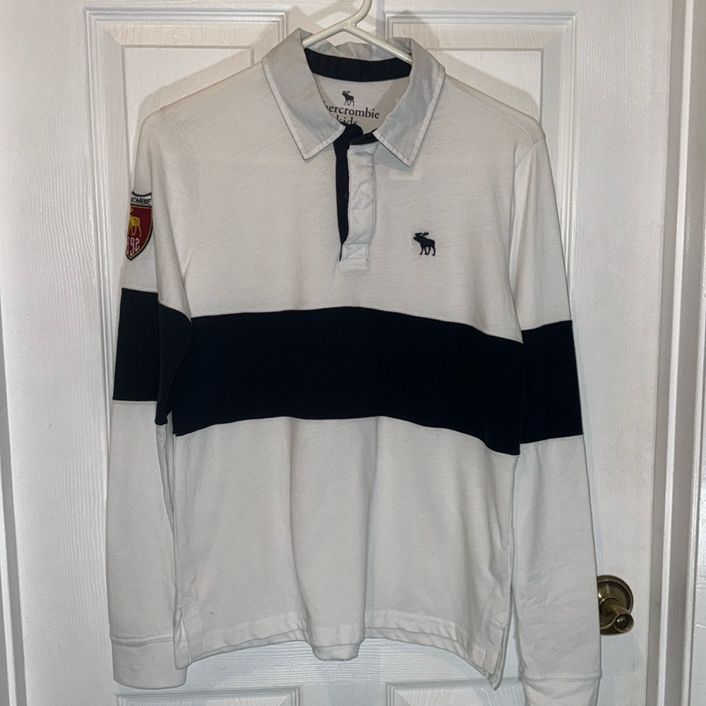 NWT Abercrombie kids rugby shirt in black and white with patch on one sleeve.